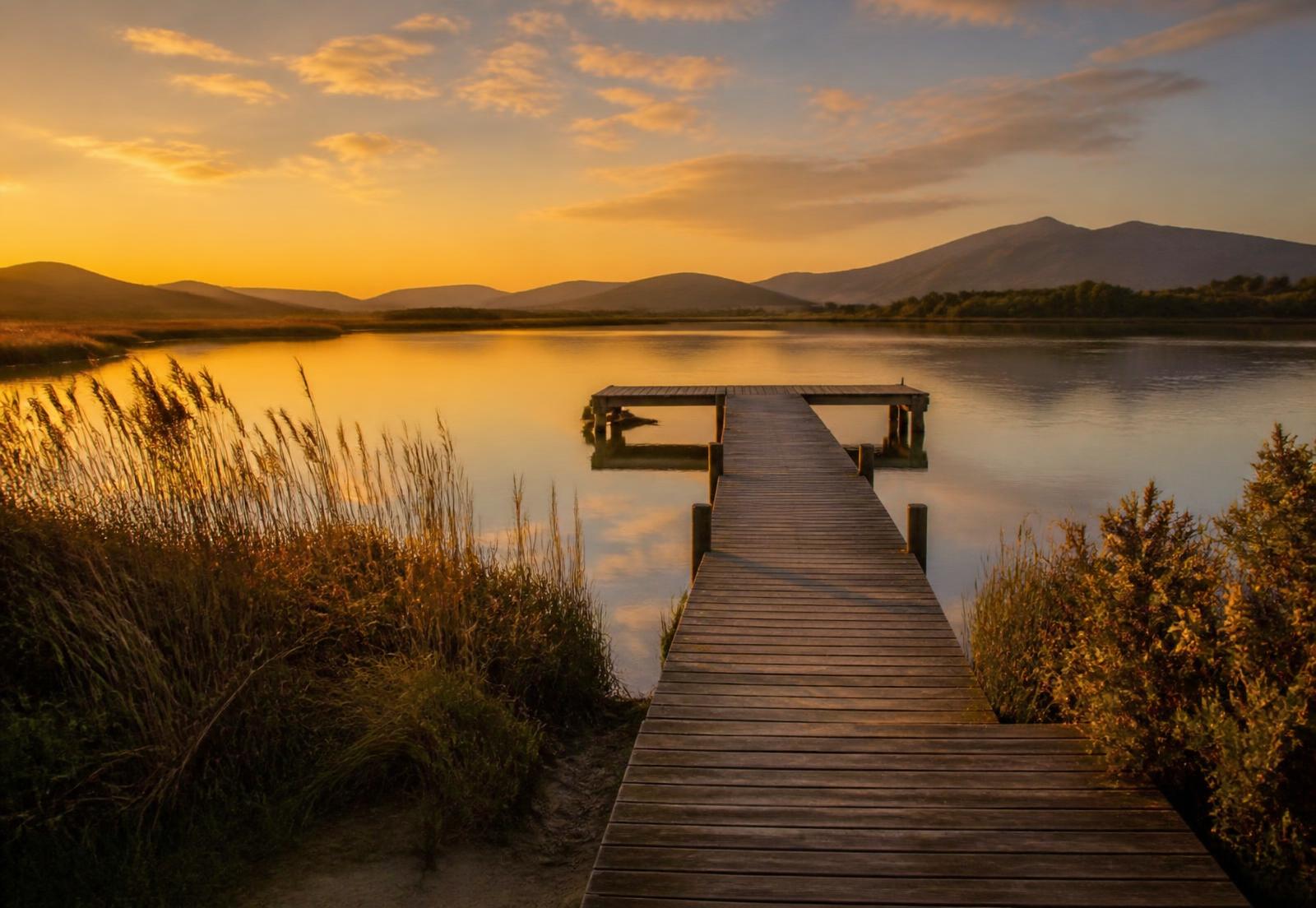 Sunset over Swartvlei Lake with a wooden jetty reaching into still water